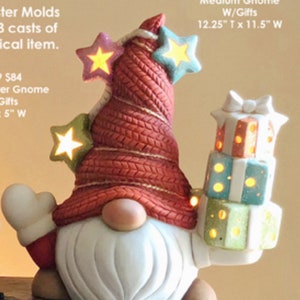 May include: A ceramic gnome figurine with a red knitted hat and a white beard. The gnome is holding a stack of presents with lights inside. The gnome is 12.25 inches tall and 11.5 inches wide.