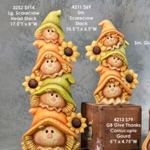 May include: A stack of four ceramic scarecrows with sunflowers, each with a different colored hat. The scarecrows are 17.5 inches tall and 8 inches wide. The scarecrows are painted in shades of orange, green, and yellow.
