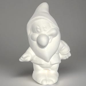 May include: White ceramic figurine of a smiling dwarf with a pointed hat and a large nose. The dwarf is standing with its arms outstretched.