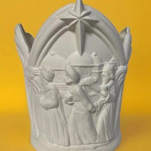 May include: A white ceramic candle holder with a star on top and a relief of the three wise men. The text "Border City Ceramics" is at the bottom. The candle holder is on a yellow background.