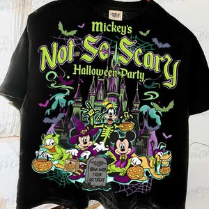 以下が含まれることがあります： ハロウィーンのデザインが施された黒いTシャツ。「Mickey's Not-So-Scary Halloween Party」の文字、漫画のキャラクター、お城、コウモリ、クモの巣が描かれています。キャラクターはジャック・オ・ランタンを持っています。