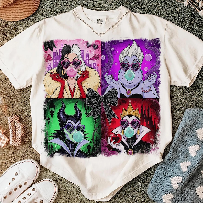 May include: White t-shirt featuring four cartoon portraits of Disney villains, each blowing a bubblegum bubble and wearing heart-shaped sunglasses. The villains are Cruella de Vil, Ursula, Maleficent, and the Evil Queen.