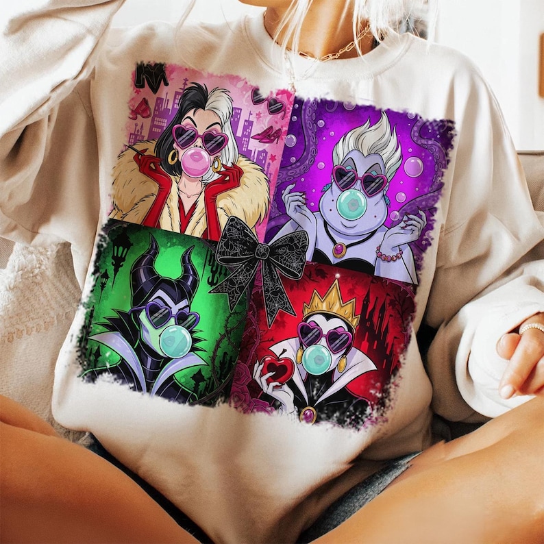 May include: Cream-colored sweatshirt featuring a graphic of four cartoon villains blowing bubble gum bubbles. Each villain is framed in a different color: red, purple, green, and red. A black bow is centered between the images.
