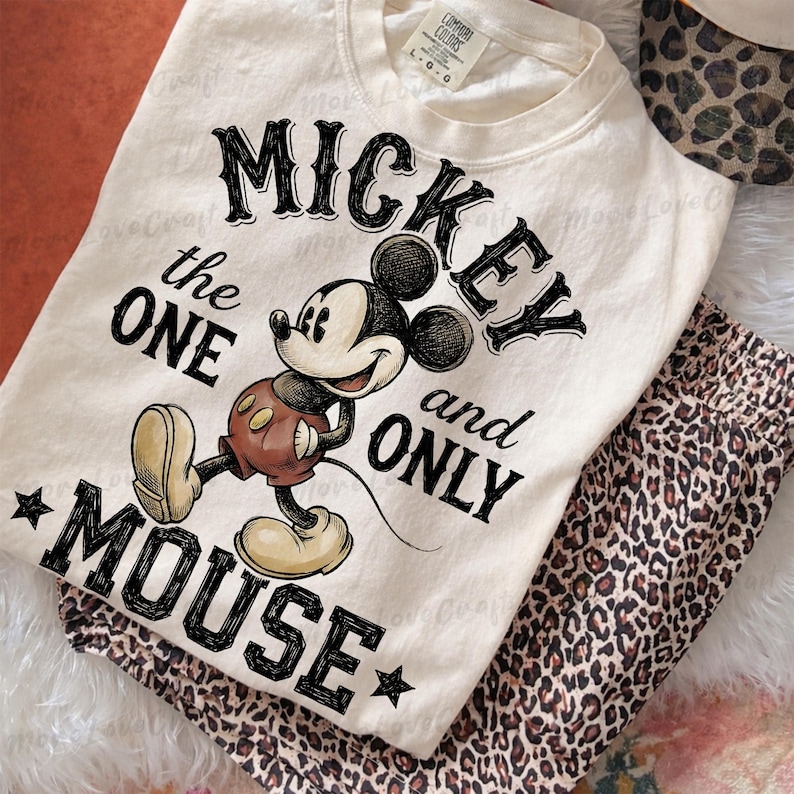 May include: Cream-colored sweatshirt featuring a graphic of Mickey Mouse with the text "Mickey the One and Only Mouse." The design includes a cartoon image of Mickey in his classic outfit. Paired with leopard print pants.
