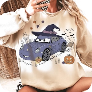 Puede incluir: Sudadera beige con un dise&ntilde;o de coche de dibujos animados con tem&aacute;tica de Halloween. El coche lleva un sombrero de bruja y est&aacute; decorado con telara&ntilde;as, calabazas, murci&eacute;lagos y velas. Tambi&eacute;n se incluye un gato de dibujos animados en el dise&ntilde;o.