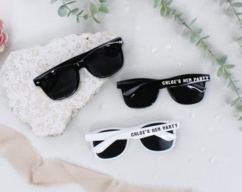 May include: Three pairs of sunglasses with black frames and lenses. Two pairs have white text on the frames that reads "Chloe's Hen Party".