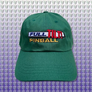 Pode incluir: Boné de beisebol verde com um logotipo bordado que diz "FULL TILT! PINBALL" em letras coloridas.