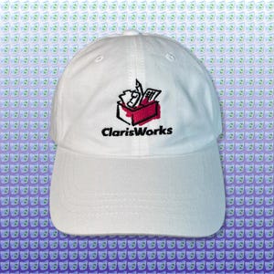 May include: White baseball cap with the embroidered "ClarisWorks" logo in black. The logo depicts a red box with office supplies. A classic, adjustable hat for everyday wear.