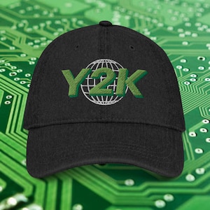 May include: Black baseball cap with the embroidered text "Y2K" in green, with a white globe design. The cap has a curved brim and a structured fit. The background features a green circuit board pattern.