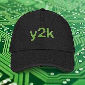 May include: Black baseball cap with the text "y2k" embroidered in green. The cap has a curved brim and a structured fit. The hat is made of a durable fabric and is suitable for casual wear.