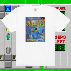 May include: White t-shirt with a retro video game box design featuring the text "Chips Challenge" and the characters from the game. The box is blue and pink with a white background. The text "US Gold" and "Epyx" are also visible on the box.
