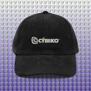 May include: Black corduroy baseball cap with the text "@CYBIKO" embroidered in white and a small yellow accent. The cap has a curved brim and an adjustable strap at the back.