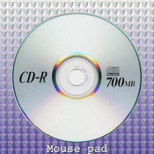 May include: A silver CD-R disc with the text "CD-R" and "700MB" printed on it. The disc has a reflective surface and a rainbow-colored inner ring. The background is a pattern of purple and white shapes.