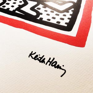 May include: A black and white illustration of a figure with a red border. The illustration is signed "Keith Haring" in black ink.