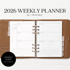 Könnte beinhalten: Ein offener A5 Wochenplaner mit braunem Lederbezug. Der Planer zeigt eine Wochenansicht mit linierten Abschnitten für jeden Tag. Der Text "2026 WEEKLY PLANNER" steht oben, darunter "A5 | Printable". Ein schwarzer Kreis mit weißem Text lautet "SUNDAY START MINI CALENDAR."