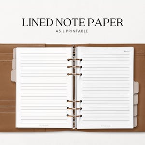 Può includere: Raccoglitore in pelle marrone aperto con carta a righe. Il testo "LINED NOTE PAPER" è in alto, con "A5 | Printable" sotto. Il raccoglitore ha un meccanismo ad anelli metallici.