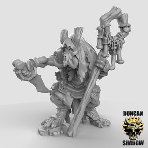 Könnte beinhalten: Eine graue, dreidimensionale Figur einer Fantasie-Kreatur, möglicherweise ein Ork oder Goblin, die eine gebogene Klinge und einen mit Knochen verzierten Stab hält. Die Figur ist detailliert mit Rüstung und einem gehörnten Helm. Das Logo "DUNCAN SHADOW" befindet sich unten rechts.