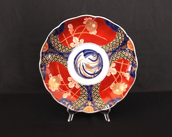 May include: A large, red and blue ceramic plate with a scalloped edge. The plate is decorated with a floral pattern and a central design of a stylized wave.