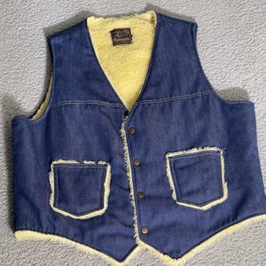 May include: A vintage denim vest with a yellow sherpa lining and trim. The vest has two front pockets and a button-up closure. The label reads "Ramsgate".