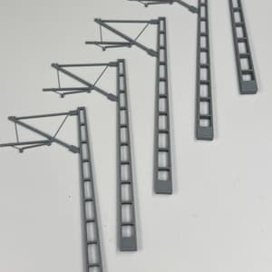 May include: A set of grey model railway overhead catenary poles. The poles have a rectangular design with cut-out sections and are topped with crossbeams and support wires, designed to hold electrical wires.