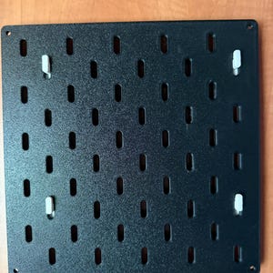 May include: A white ceramic mug with a black handle and the text "But First, Coffee" in a bold, black font. The mug is set against a blurred background, suggesting a cozy setting.