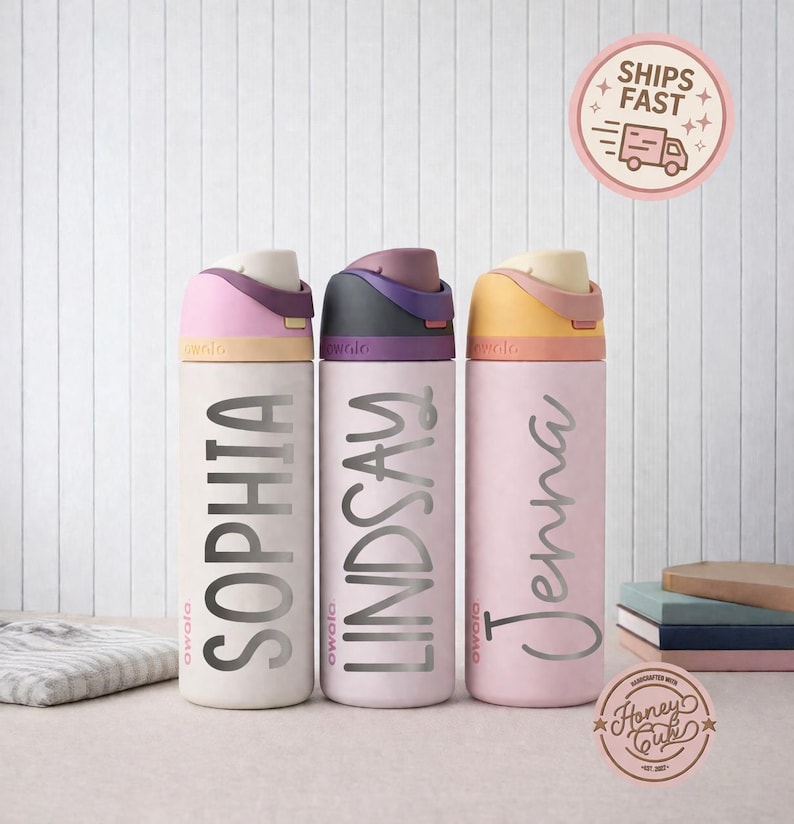 May include: Three personalized water bottles in cream, light pink, and pink. Each bottle has a different name in silver script: Sophia, Lindsay, and Jenna. The lids are colored in shades of purple, black, and yellow. The bottles are on a white background.