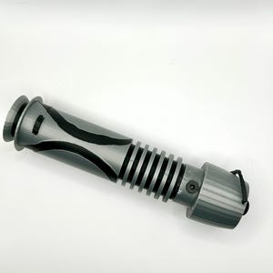 Peut inclure: Un accessoire de sabre laser gris avec des accents noirs et une surface textur&eacute;e. Le sabre laser a un cordon noir attach&eacute; &agrave; l'extr&eacute;mit&eacute;.