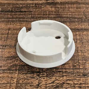 May include: White plastic round base with a small hole in the center and three slots around the edge.