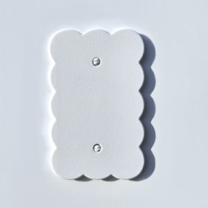 May include: White wall plate with a scalloped edge and two screw holes.