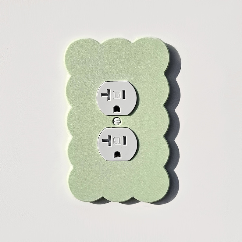 May include: A light green scalloped wall plate with two white electrical outlets.