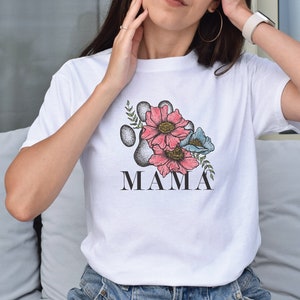 Peut inclure: T-shirt blanc avec un motif d'empreinte de patte florale et le mot "MAMA" imprimé en dessous.