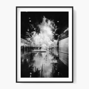 Puede incluir: Lámina artística enmarcada en blanco y negro. La fotografía representa una formación en forma de nube en un pasillo con suelo reflectante. La imagen tiene un alto contraste, siendo la forma de nube el elemento más brillante.
