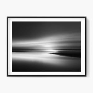 Puede incluir: Impresión enmarcada en blanco y negro de un paisaje marino. La imagen captura una larga exposición del océano y el cielo, con nubes y agua borrosas que crean una sensación de movimiento. La línea del horizonte es visible y la impresión está en un marco negro.