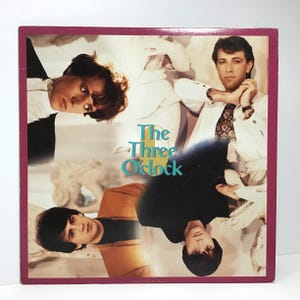 May include: Vintage vinyl record album cover featuring four band members. The album cover has a maroon border and the band name "The Three O'Clock" in teal and white. The band members are in various poses, with a light background.