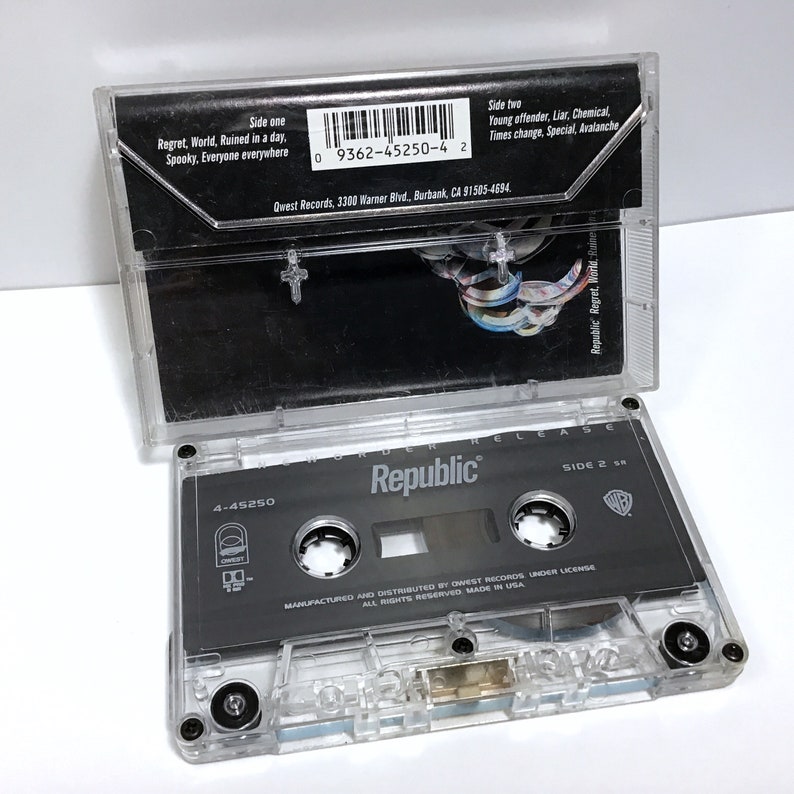 K&ouml;nnte beinhalten: Ein transparentes Plastik-Kassettengeh&auml;use mit einem schwarzen Kassettenband im Inneren. Das Kassettenband ist mit "Republic" und "Murder Release" beschriftet. Das Band ist eine Ver&ouml;ffentlichung von Warner Bros. Records. Das Geh&auml;use hat einen Barcode und den Text "9362-45250-4 2".