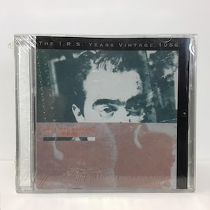 May include: Sealed vintage CD case featuring the album "Life's Rich Pageant" by R.E.M. The cover art displays a grayscale image of a person's face, with the text "THE I.R.S. YEARS VINTAGE 1986" at the top. The album title and band name are visible.