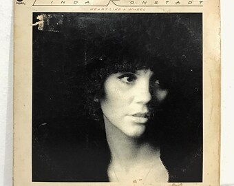 Könnte beinhalten: Vintage Vinyl-Schallplattenhülle mit Linda Ronstadt. Das Albumcover ist in Schwarzweiß gehalten und zeigt ein Porträt von Ronstadt sowie den Albumtitel "Heart Like a Wheel". Das Capitol Records-Logo ist sichtbar.