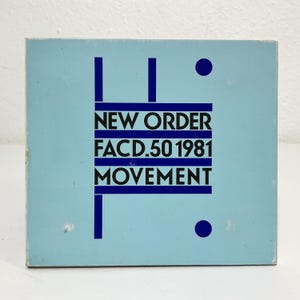 May include: A square light blue music album cover featuring dark blue geometric lines and dots. The text in black reads NEW ORDER, FACD.50 1981, and MOVEMENT, arranged between horizontal bars. The design is centered on a solid light blue background.