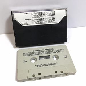 May include: A vintage cassette tape labeled "A Christmas Carousel" with a white background and black text. The tape is labeled with the title of the album, the song titles, and the artists. The tape is labeled with the text "Side Two" and "BT 15763".