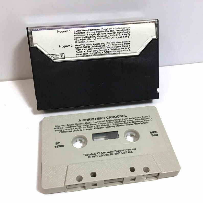 May include: A vintage cassette tape labeled "A Christmas Carousel" with a white background and black text. The tape is labeled with the title of the album, the song titles, and the artists. The tape is labeled with the text "Side Two" and "BT 15763".