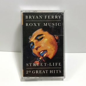 May include: A black cassette tape with a clear plastic case. The front of the tape features a photo of Bryan Ferry, the text "Bryan Ferry Roxy Music", "Street Life", and "20 Great Hits".