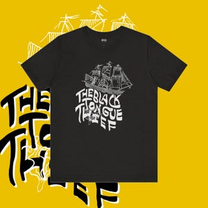 Può includere: T-shirt nero con una grafica bianca di una nave e il testo "The Black Tongue Thief".