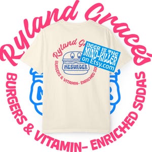 Könnte beinhalten: Cremefarbenes T-Shirt mit einem kreisförmigen Design in Rosa und Blau. Das Design enthält den Text "Ryland Graces Burgers & Vitamin-Enriched Sodas", eine blaue und rote Burger-Grafik mit dem Wort "MEBURGER" und ein blaues Rechteck mit "BEER IS THE MIND-KILLER on Etsy.com".