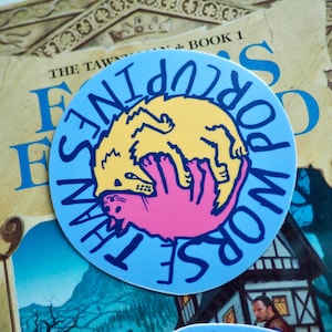 May include: A circular sticker with a light blue backdrop and the words "Worse Than Porcupines" in dark blue. It shows a yellow animal and a pink hand. The sticker is placed on a book.
