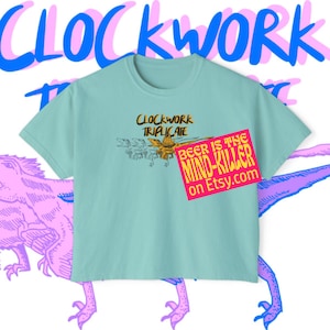 May include: A pale blue t-shirt featuring the text "CLOCKWORK TRIPLICATE" and an insect graphic. A pink and blue dinosaur graphic is in the background. A pink and yellow sticker reads "BEER IS THE MIND-KILLER on Etsy.com."