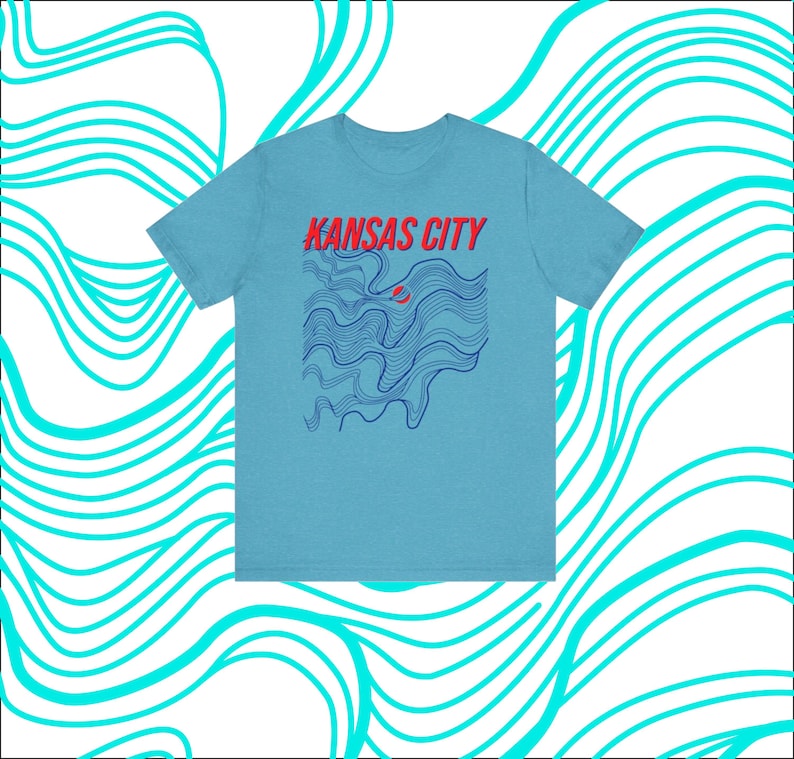 May include: A light blue t-shirt with a graphic design of blue and red wavy lines. The text "KANSAS CITY" is printed in red on the shirt.