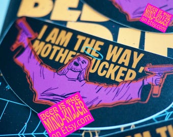 May include: A collection of stickers with a black background and yellow and purple text. The stickers feature a cartoon image of Jesus holding a gun, with the text "I AM THE WAY MOTHERFUCKED". A pink sticker reads "BEER IS THE MIND-KILLER on Etsy.com".
