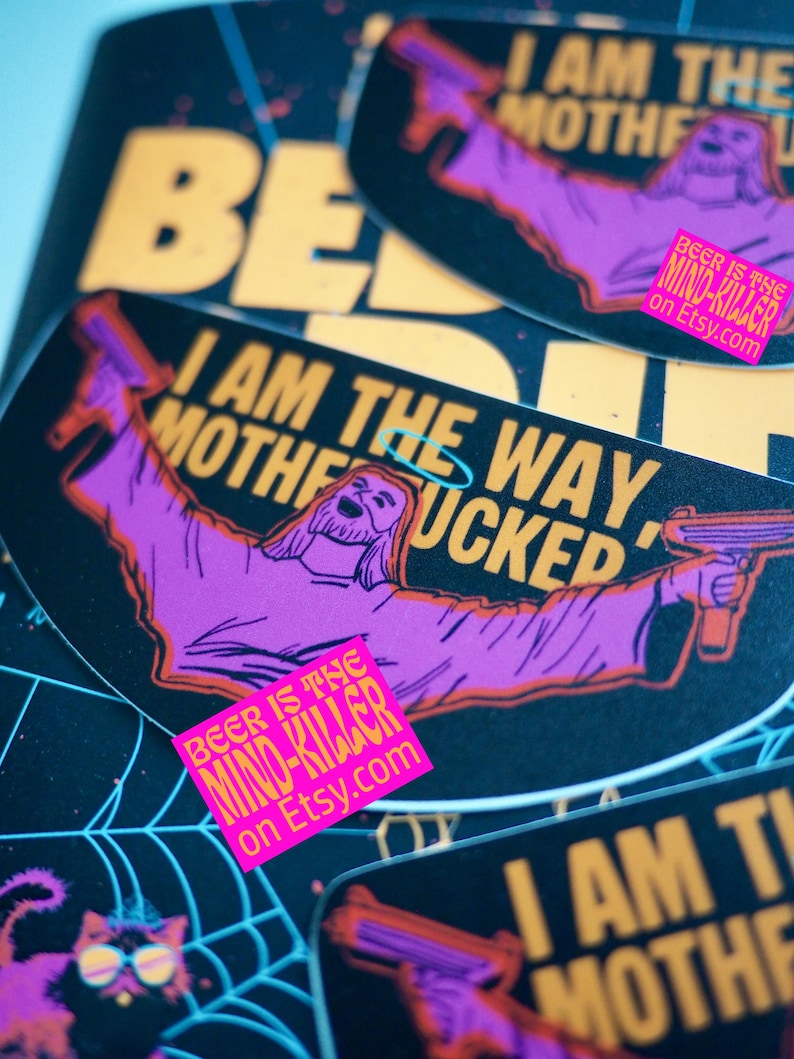 May include: A collection of stickers with a black background and yellow and purple text. The stickers feature a cartoon image of Jesus holding a gun, with the text "I AM THE WAY MOTHERFUCKED". A pink sticker reads "BEER IS THE MIND-KILLER on Etsy.com".