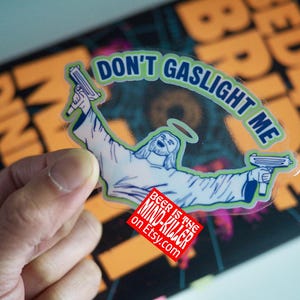 May include: A transparent sticker featuring an illustration of a figure with a halo, holding two guns, with the text "DON'T GASLIGHT ME". A red square with white text reads "BEER IS THE MIND-KILLER on Etsy.com".