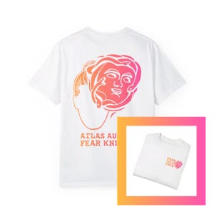May include: White t-shirt with a pink and orange gradient graphic of a woman's face with snakes on the back. The front of the shirt has the text "FEAR HAS NO FACE" in pink and orange.